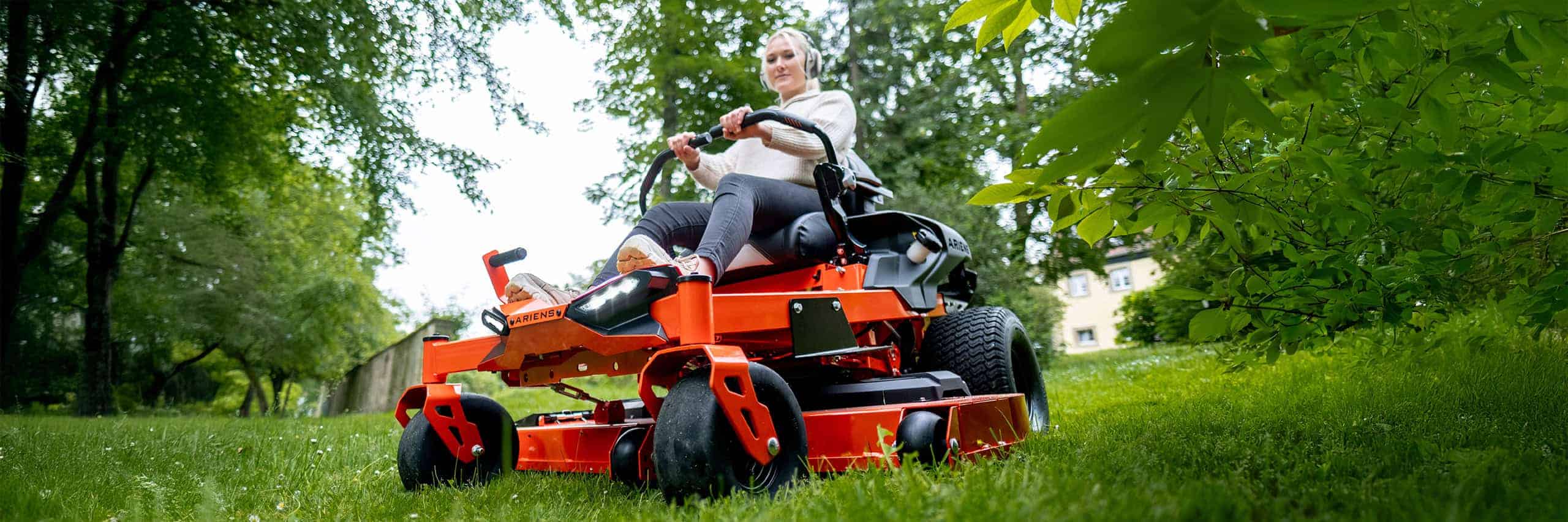 Wide close-up shot of a Ariens Zero-Turn mower IKON, a woman mowing lawn