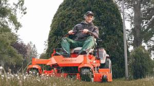 Professional mowing with an Ariens zero-turn mower on a wet lawn in rainy conditions