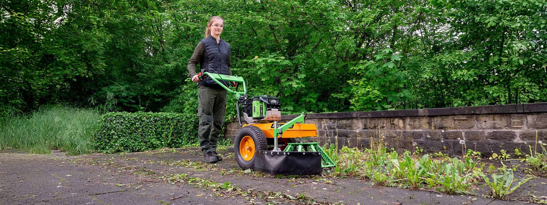 Woman using an AS-Motor WeedHEX for removing mechanically weeds on the floor