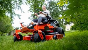 Wide close-up shot of a Ariens Zero-Turn mower IKON, a woman mowing lawn