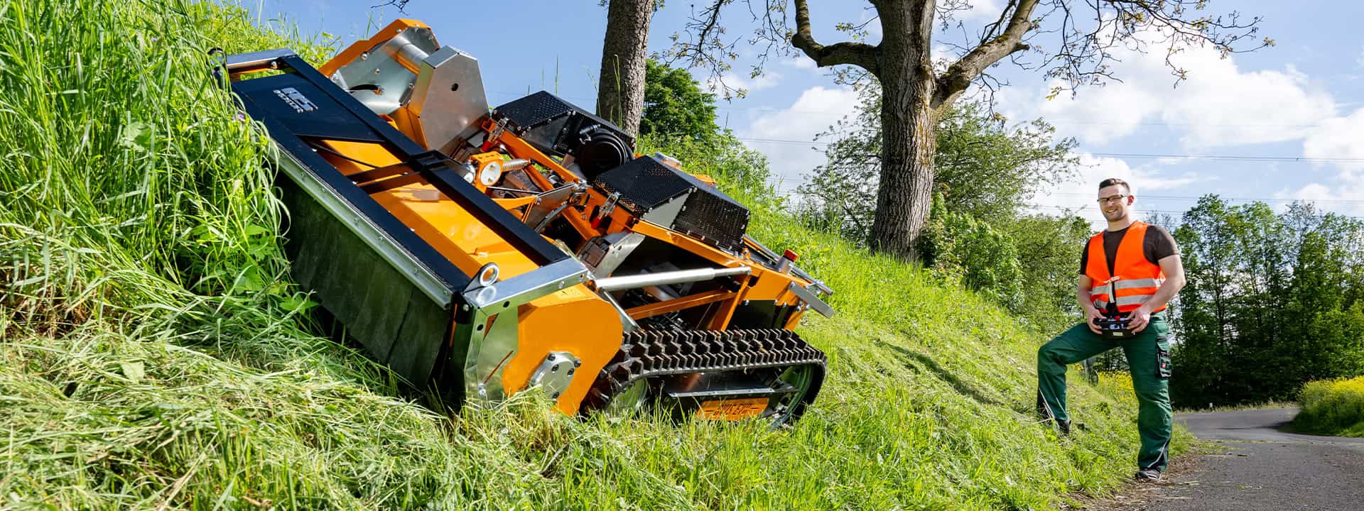 Man using an AS-Motor remote controlled flail mower, AS 1000 Ovis EVO, cutting high grass on a steep slope