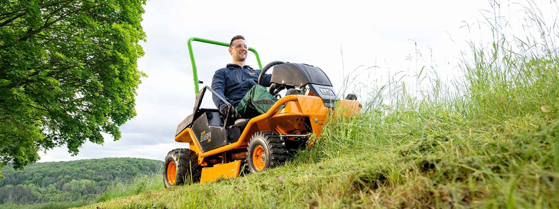 Man using an AS-Motor ride-on-mower, AS 920 E-Sherpa 2WD, mowing high gras on steep slopes