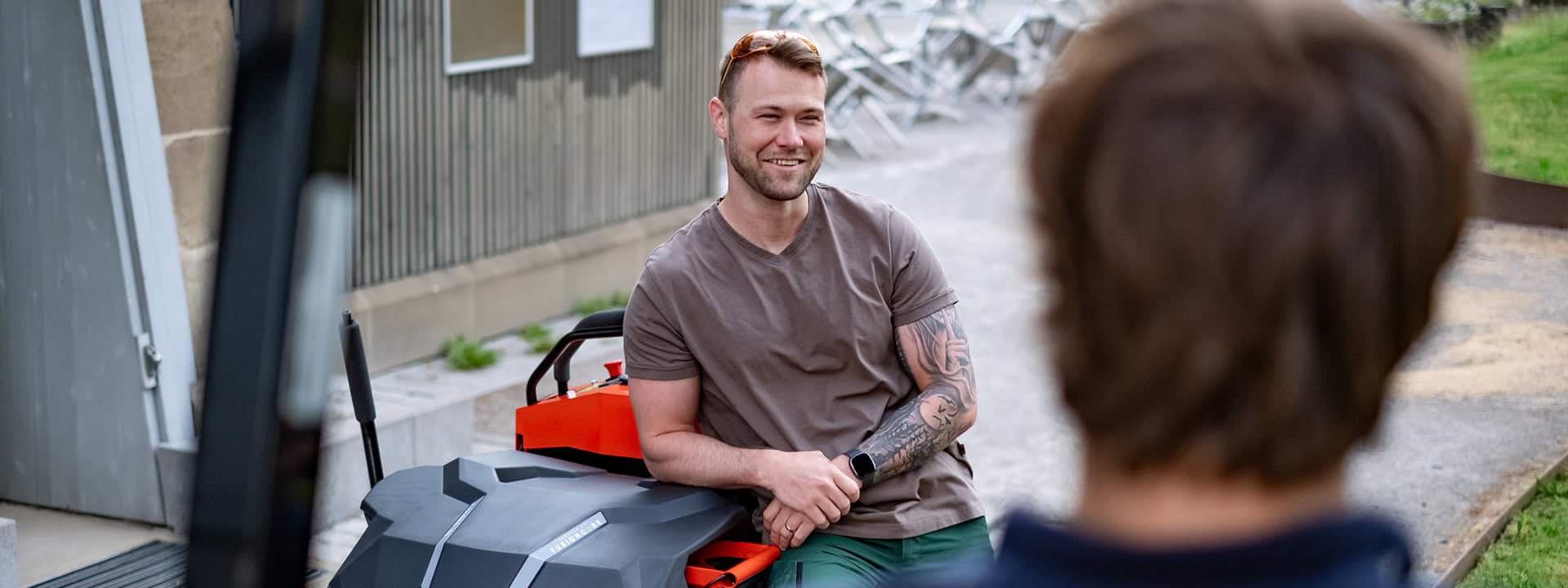 Smiling man leaning against a Ariens Zero-Turn mower