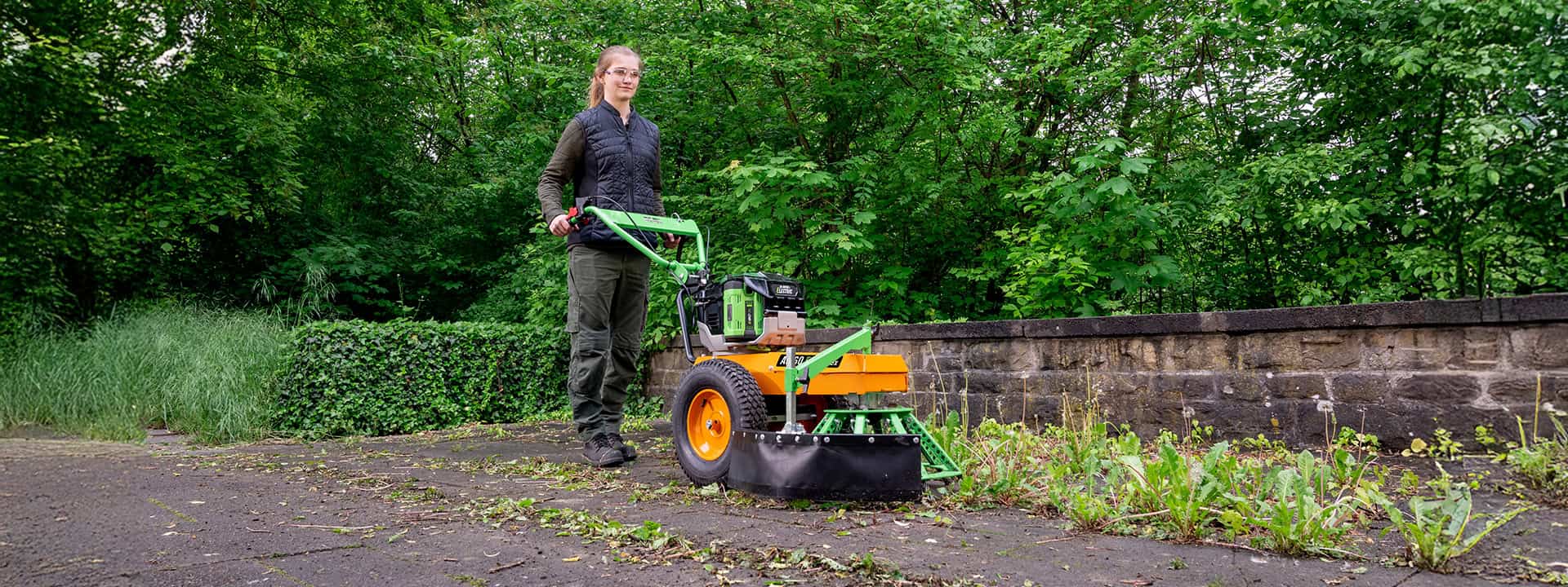 Woman using an AS-Motor WeedHEX for removing mechanically weeds on the floor