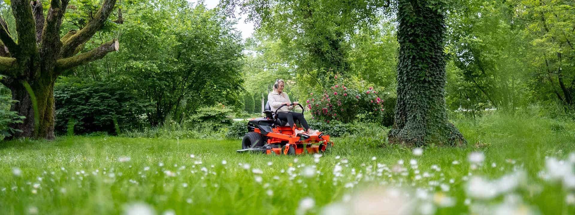 Wide shot of a Ariens Zero-Turn mower IKON, a woman mowing lawn