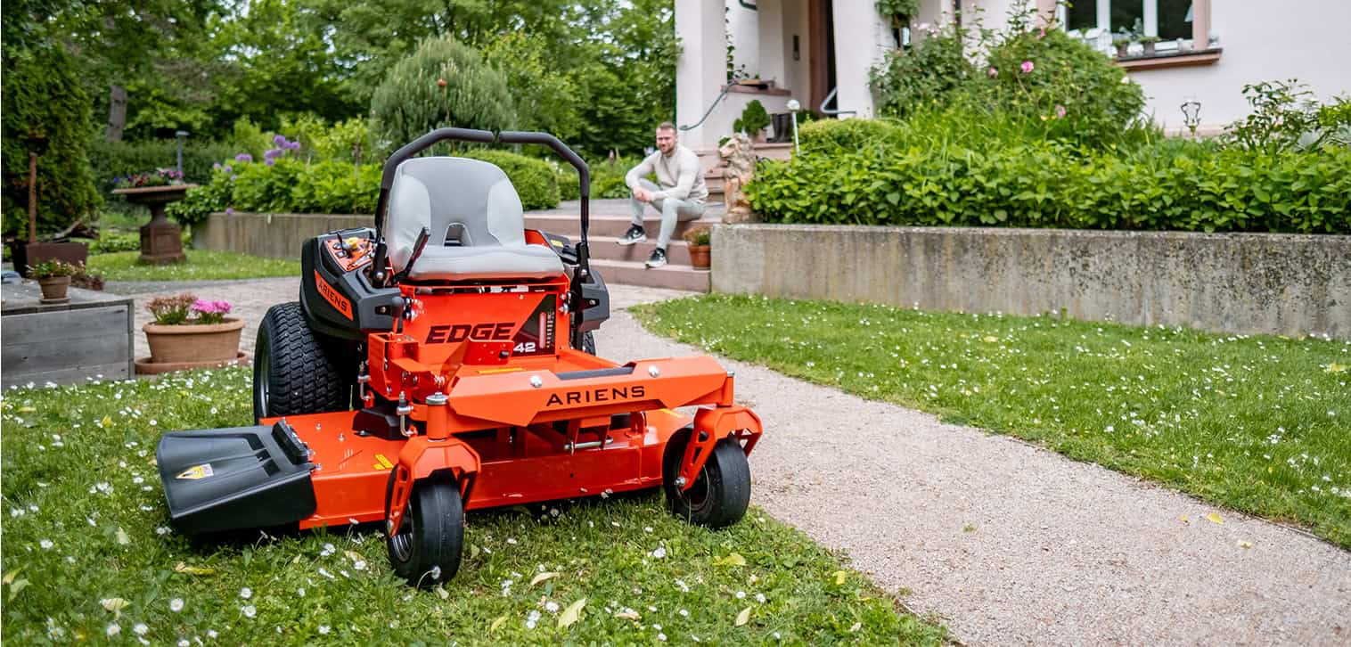 Ariens Zero-Turn Mower model EDGE, showcasing efficient mowing with zero-turn features. Happy young man is mowing the lawn with an Ariens Zero-Turn mower