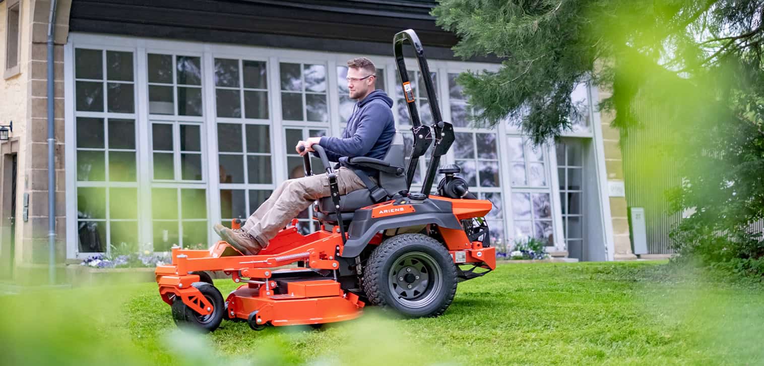 Ariens Zero-Turn Mower model ZENITH, showcasing efficient mowing with zero-turn features. Happy young man is mowing the lawn with an Ariens Zero-Turn mower